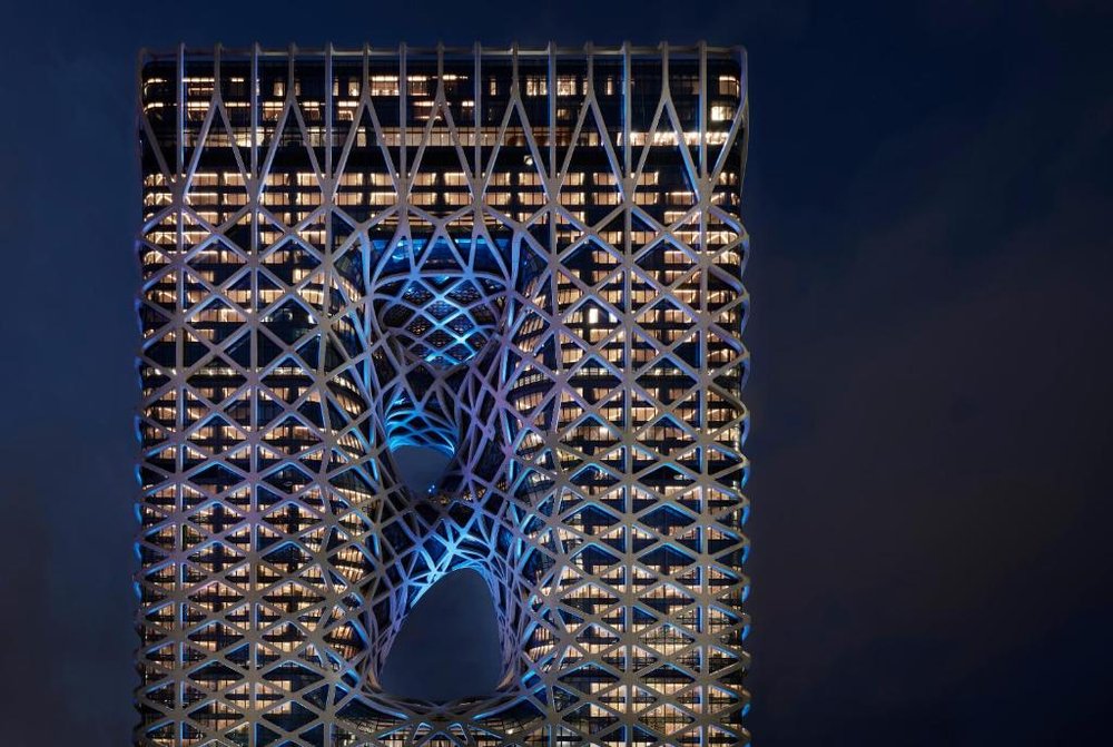 Fachada de Morpheus de noche: un exoesqueleto blanco de acero con dos vacios que atraviesan la torre